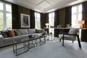 Additional image of a modern living room with glass tables, custom bookshelves and area carpet.